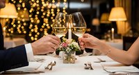 Elegant couple toasting with champagne glasses at romantic dinner table with bokeh lights background for anniversary celebration and fine dining occasions.