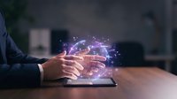 Businessman hands hovering over tablet with glowing digital network connections and data visualization effects in modern office environment.