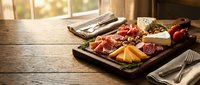 Gourmet charcuterie board with assorted meats, cheeses, fruits and nuts on rustic wooden table in warm sunlight for entertaining and food photography.