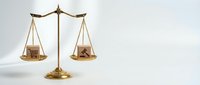 Golden brass balance scale with wooden house models on white background representing real estate investment decisions and property market evaluation.