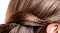 Silky smooth brown hair close-up showing healthy, shiny strands twisted in an elegant wave pattern against soft natural lighting, demonstrating hair care and beauty concepts.