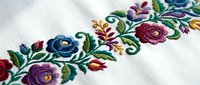 Colorful floral embroidery with roses and leaves on white fabric showcasing traditional needlework craftsmanship for textile and fashion design projects.