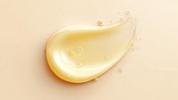 Golden liquid drop with small bubbles on beige background, glossy cosmetic serum or oil texture with light reflection and smooth flowing shape.