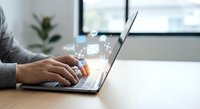 Professional businessman typing on laptop with digital communication icons floating above keyboard in modern office workspace for business technology concepts.