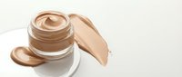 Luxury foundation cream jar with smooth beige makeup smears on white background. Premium cosmetic product for skincare and beauty routine isolated.