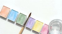 Watercolor paint palette with six pastel colors and brush for artistic projects and creative design work.