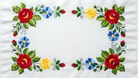 Traditional folk art floral embroidery frame with red roses, yellow and blue flowers on white fabric background. Decorative border design for crafts and textiles.