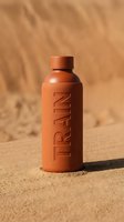 Orange sunscreen bottle with embossed text on sandy beach background, ideal for skincare, cosmetics, beauty product marketing, wellness advertising, and summer sun protection campaigns.