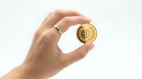 Hand holding golden cryptocurrency coin between fingers on white background for financial investment and digital currency concepts.