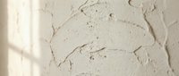 Cracked and peeling white paint on textured wall surface showing weathered deterioration and aging damage for renovation and repair projects.