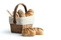 Fresh crusty bread loaves and wheat ears in rustic wicker basket with white linen. Artisanal bakery composition on white background, isolated.