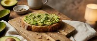 Fresh avocado toast on rustic wooden board with lime, seeds and coffee mug. Healthy breakfast meal ready for morning nutrition and wellness lifestyle.