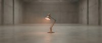 Vintage brass desk lamp glowing in empty concrete industrial loft space, minimalist interior design concept for modern workspace and creative studio environments.