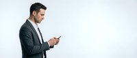 Middle-aged Caucasian male professional in dark business suit and tie using smartphone, isolated on white background for corporate and business applications.