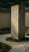 Tall rectangular stone pillar with textured granite surface standing in zen garden with raked gravel and moss, suitable for architecture and landscape design projects.
