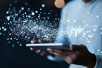 African American hands holding digital tablet with glowing blue particles and light effects streaming from screen, representing digital transformation and technology innovation.