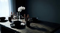 Dark elegant dining table setting with black plates, copper candle holders and white orchid centerpiece for luxury home decor and entertaining.