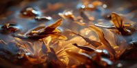 Autumn leaves floating on water surface with golden sunlight creating reflective highlights and warm amber tones.
