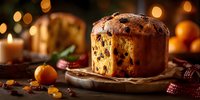 Traditional panettone Christmas bread with candied fruits and raisins on wooden board with warm bokeh lights creating festive holiday baking atmosphere.