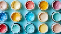 Colorful acrylic paint jars in pastel and bright tones arranged in rows on turquoise background, top view composition showing texture and swirls in paint surface.