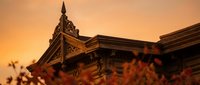 Historic ornate building architecture with decorative spire against warm sunset sky creating dramatic golden hour lighting for travel and heritage concepts.