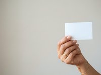 Hand holding blank white card or ticket against neutral beige background, suitable for business branding, marketing mockups, and promotional material design.
