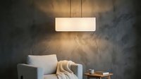 Modern minimalist interior with gray upholstered armchair, warm pendant lighting, and textured concrete wall. Ideal for home decor, furniture, and interior design projects.