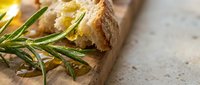 Fresh artisan bread with rosemary herbs on rustic wooden cutting board, homemade bakery concept for culinary blogs and restaurant menus.