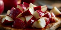 Fresh red apples cut into juicy chunks on wooden cutting board, ready for cooking or snacking.