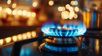 Gas stove blue flame burning with golden bokeh lights in background, close up view of kitchen burner showing energy consumption and cooking concept.