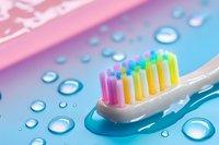 Colorful toothbrush with rainbow bristles on wet surface with water droplets for dental hygiene and oral care routine.