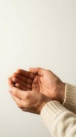 Elderly hands cupped together in receiving gesture wearing beige knit sweater against neutral background for charity and support concepts.