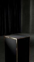 Elegant black pedestal with gold trim in a dark moody studio setting, perfect for luxury product display and showcase presentations.