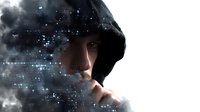 Young Asian man in black hood surrounded by digital particles and smoke effects, representing cybersecurity, hacking, or digital transformation concept.