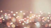 Romantic pink and gold bokeh background with glowing heart shapes and light effects for Valentine's Day designs and love-themed projects.