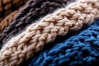 Close-up macro shot of knitted wool texture in brown, beige and blue colors showing detailed yarn pattern and fabric structure. Soft winter material background.
