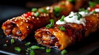 Glazed meat rolls with herbs and sour cream sauce on dark plate. Gourmet appetizer ready for restaurant menu or cooking blog content.