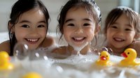 Young Asian girls laughing and playing in bubble bath with yellow rubber ducks, showing genuine joy and happiness during bath time fun. Authentic family moment.