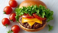 Delicious cheeseburger with beef patty, melted cheese, fresh lettuce and tomato on sesame bun. Perfect for restaurant menus and food advertising.
