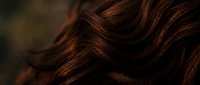 Luxurious brown hair with rich copper highlights flowing in soft waves, showcasing natural texture and shine for beauty and haircare concepts.