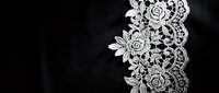 Delicate white lace border with intricate floral and geometric patterns isolated on black background, suitable for wedding invitations, greeting cards, and design overlays.
