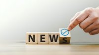 Hand placing wooden cube with checkmark completing word NEWS on desk for business communication and media updates.