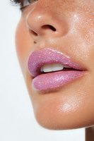 Close-up of glossy pink glitter lips with sparkle effect on light skin tone model showing partial face profile against white background for beauty and cosmetic advertising.