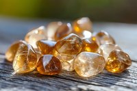 Raw citrine crystals scattered on rustic wooden surface in natural sunlight, showcasing golden amber hues and translucent mineral formations with light reflections.