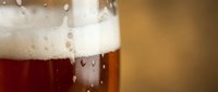 Close-up of cold beer glass with condensation droplets and foam head, perfect for beverage, brewery, and pub advertising campaigns.