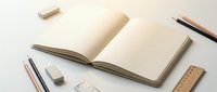 Open blank notebook with empty pages surrounded by wooden stationery items including pencils, ruler and eraser on clean white background for creative projects.