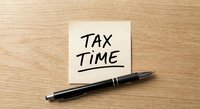 Tax time reminder note with black pen on wooden desk for accounting and financial planning preparation.