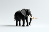 Miniature African elephant figurine with long ivory tusks cast dramatic shadow on white background, isolated minimal composition for creative design projects.