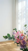 Colorful sweet pea flowers with eucalyptus leaves in bright sunlit room with white curtains and wooden floor creating peaceful home atmosphere.
