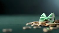 Mint green bow tie resting on scattered gold coins against dark green background with shallow depth of field, symbolizing financial success and elegance.